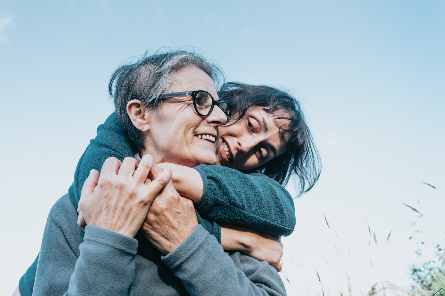 an older woman hugging another elderly women in the outdoors