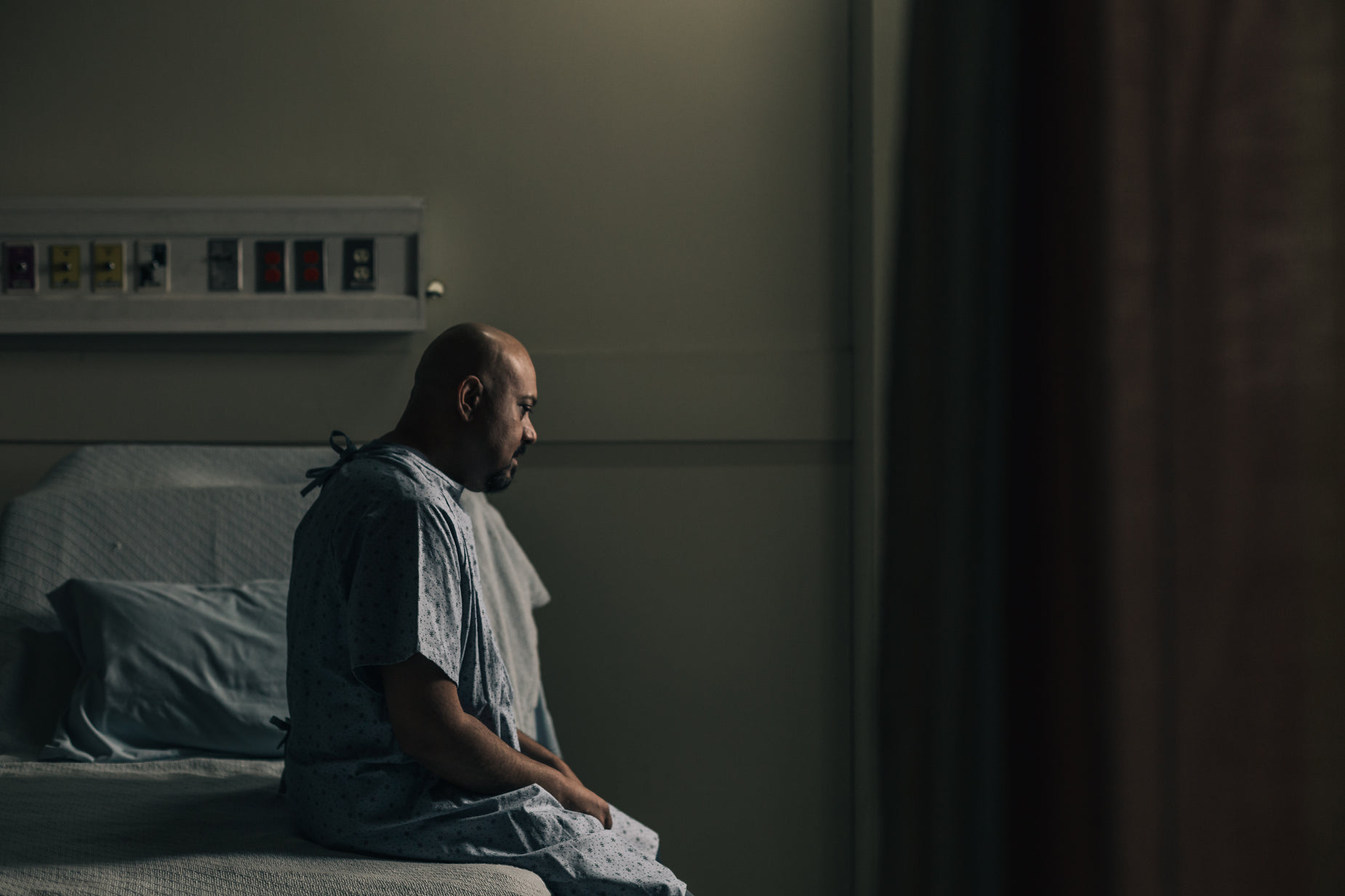 a man sits in a dimly lit room in front of a window