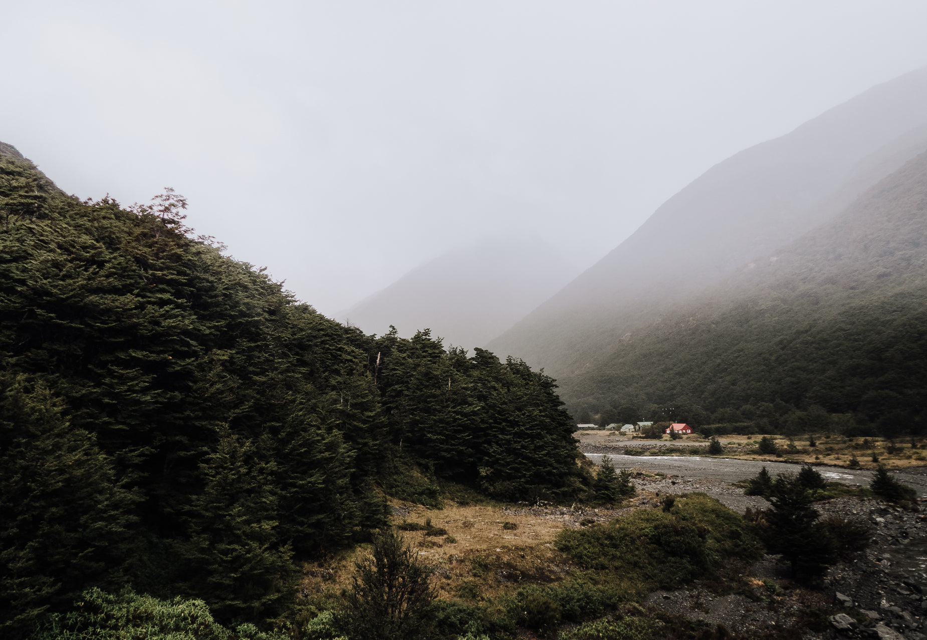 a mountain with a stream in it and small cabins nestled between some trees