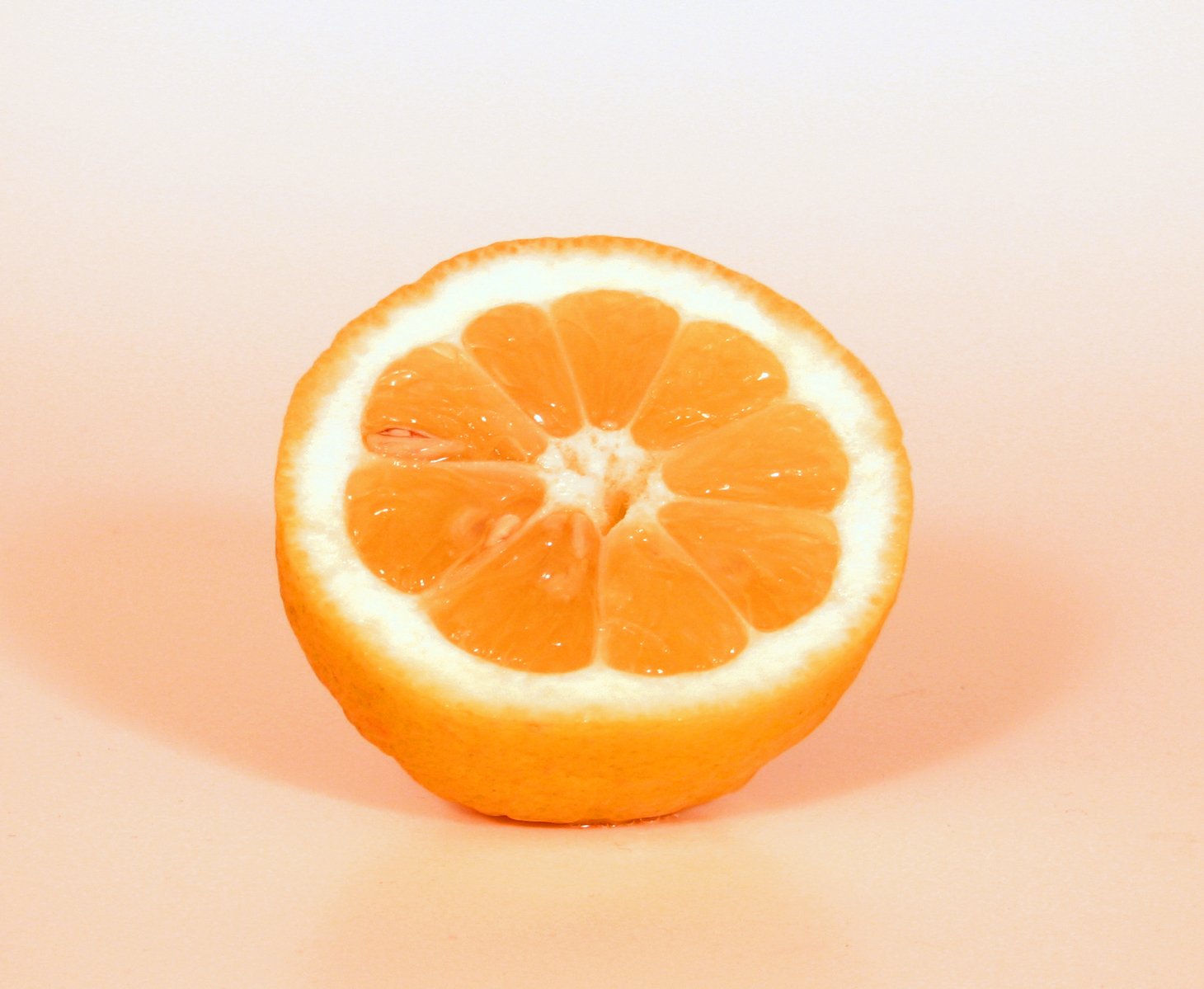 a half of an orange sitting on top of a white surface