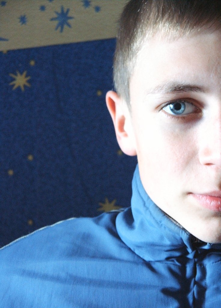 boy looking at the camera with blue shirt and stars on it