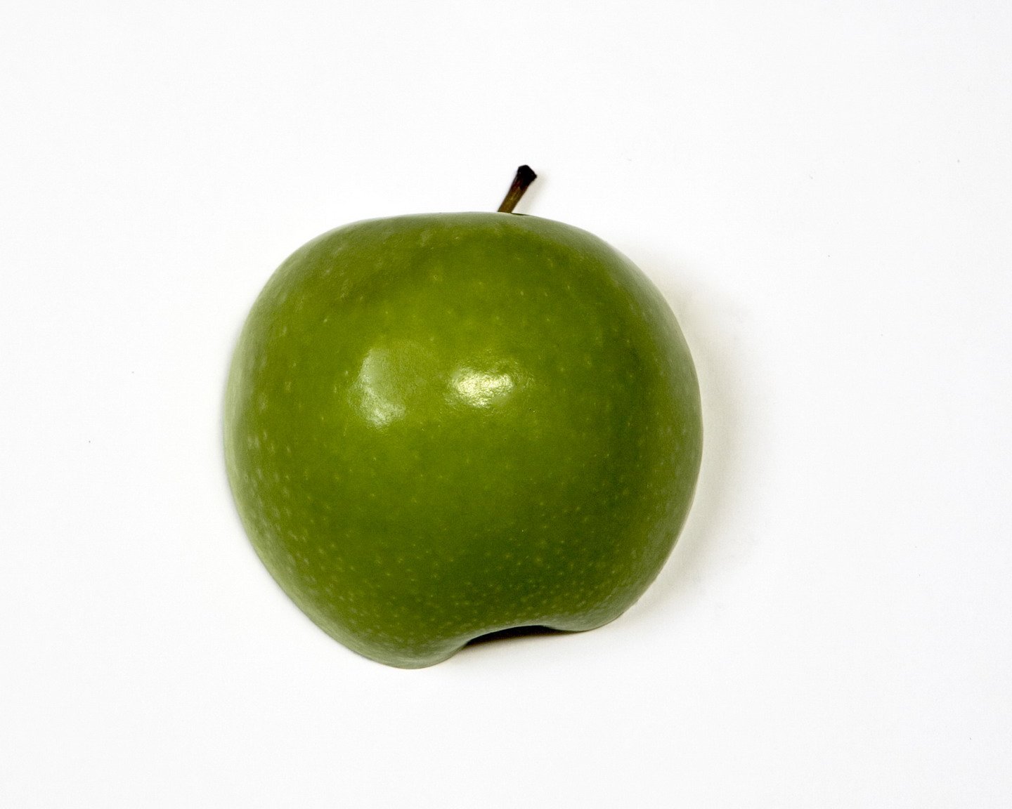 the green apple is against a white backdrop