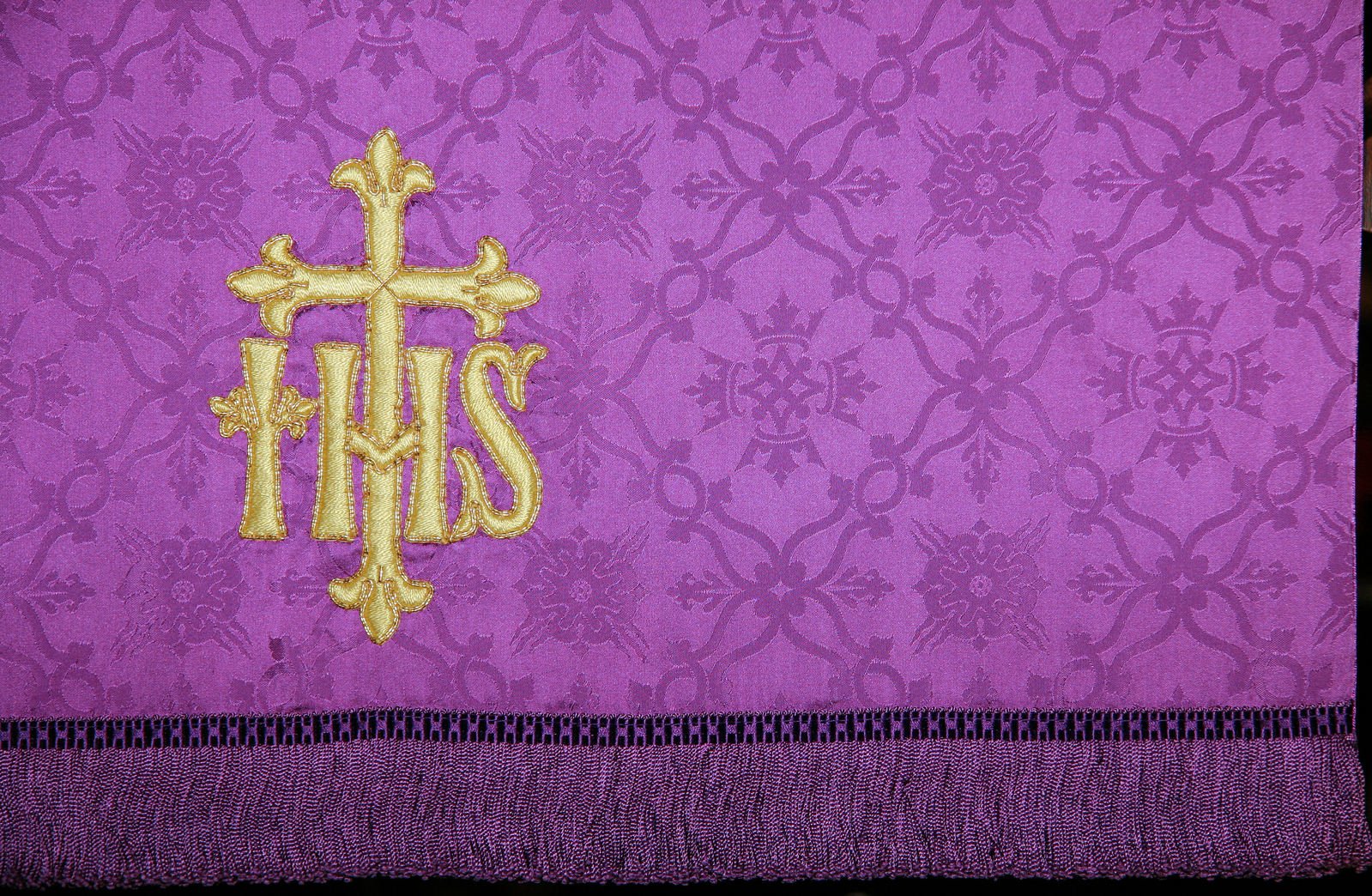 cross on purple fabric with gold embroidered letters