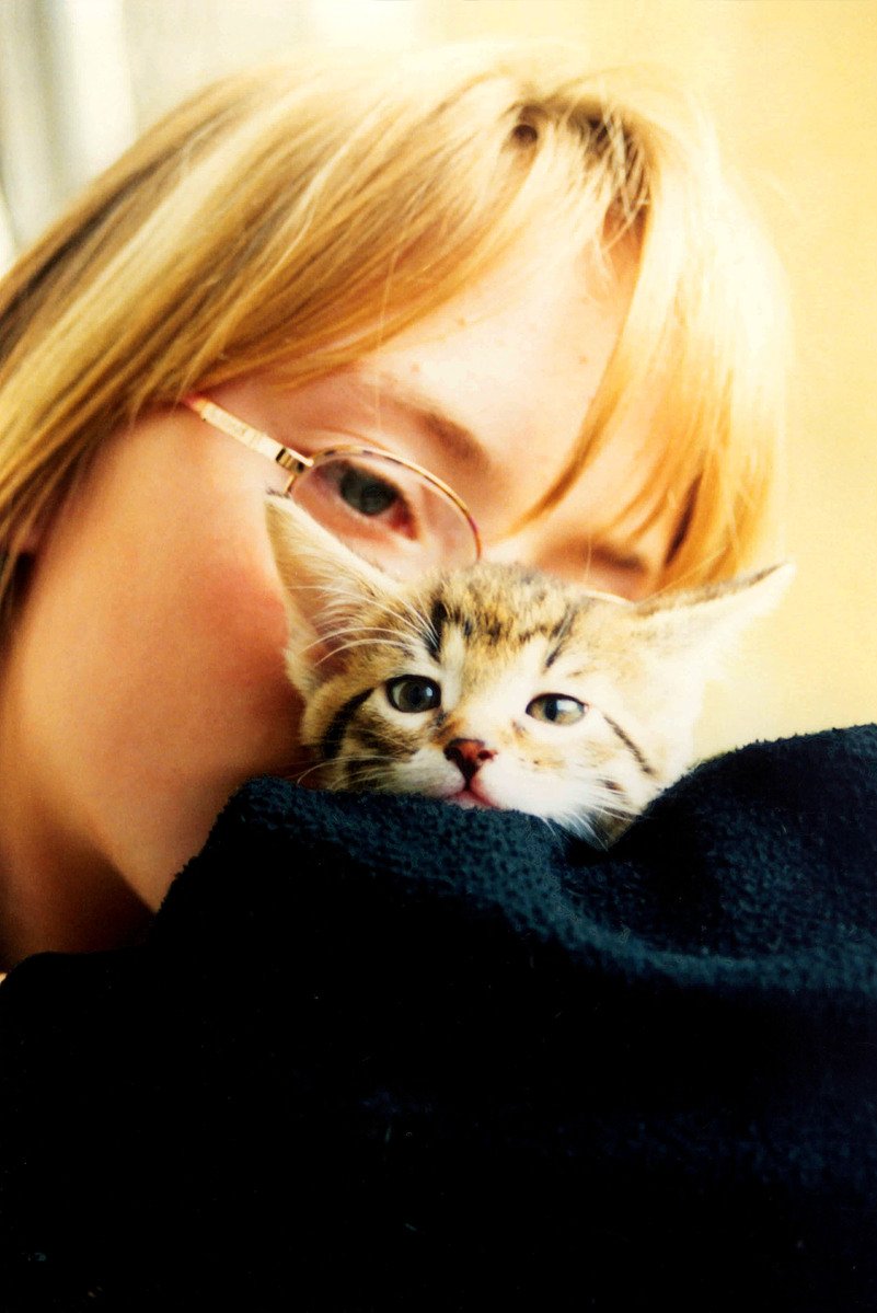 a woman is holding a small kitten up to her face