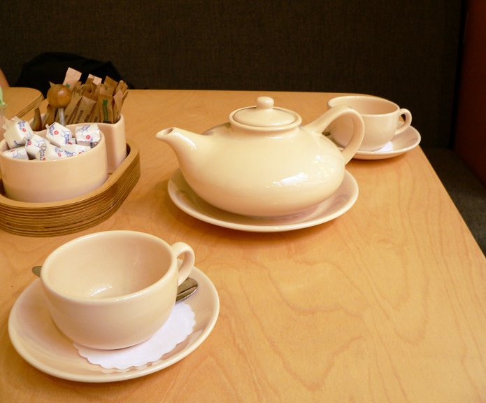 there is a tea pot, plate, and cup on the table