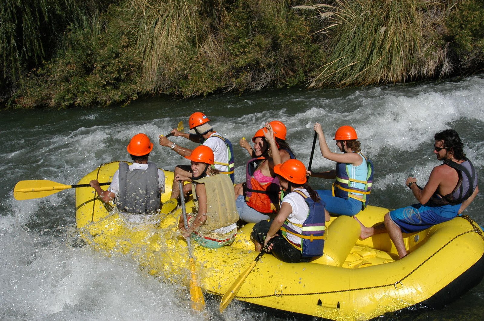 a group of people riding on the back of a yellow raft