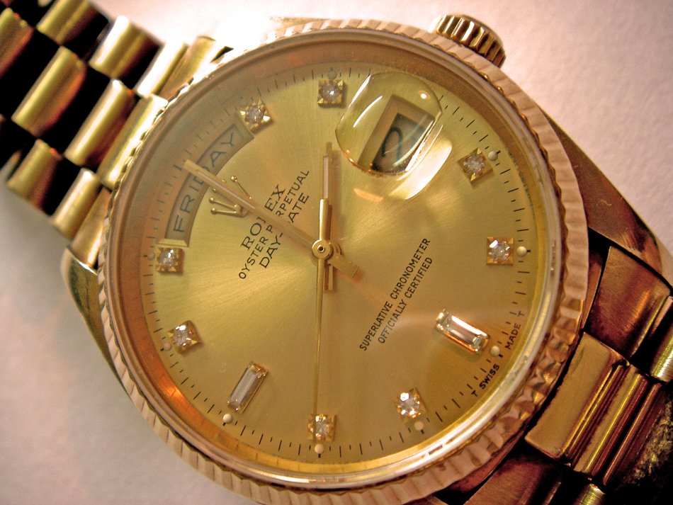 a gold watch sitting on top of a black and white clock