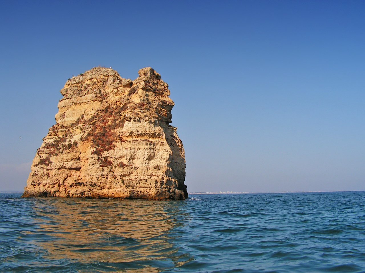 a large rock sticking out of the ocean water