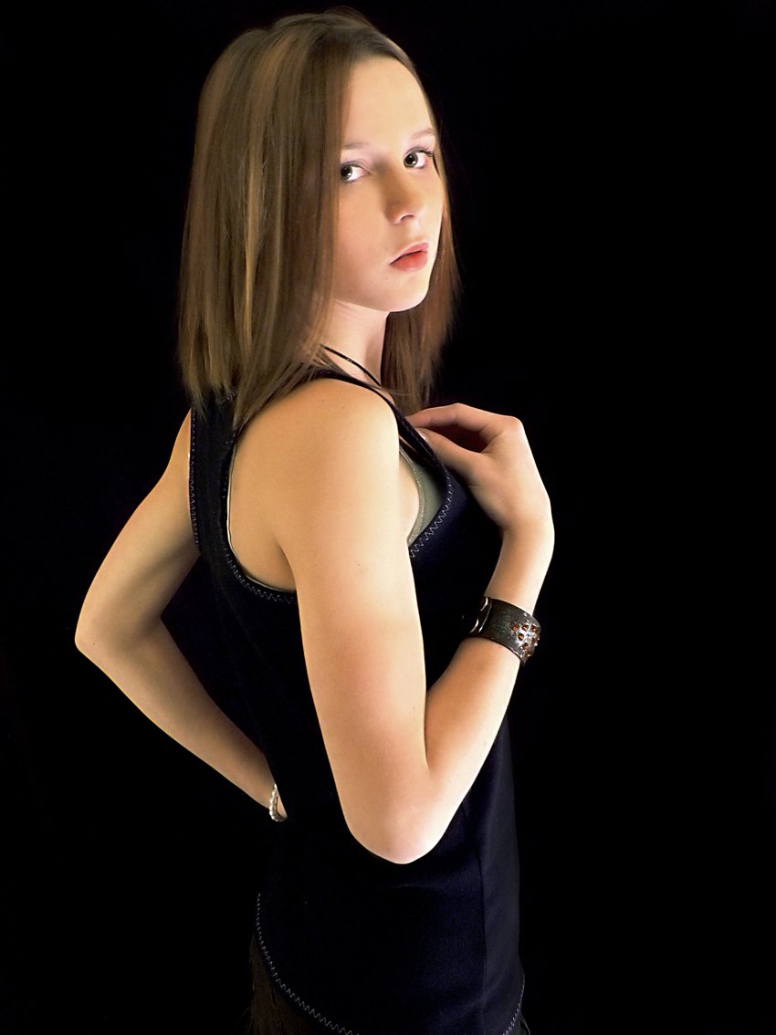 young woman in black with arm crossed, posing for a portrait