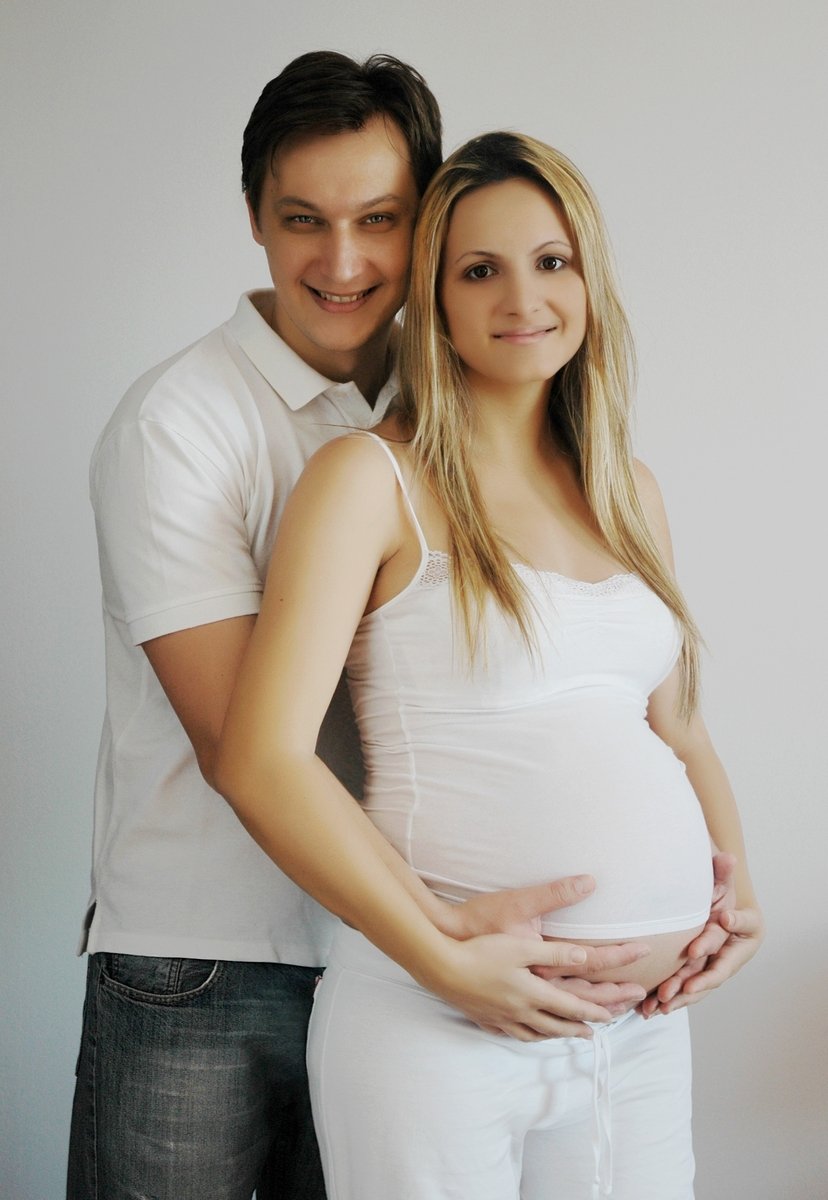 pregnant couple posing for picture against white background