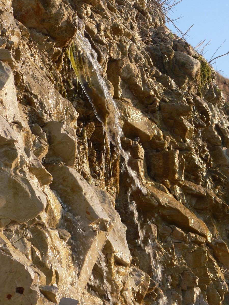 water coming down the sides of a rocky cliff