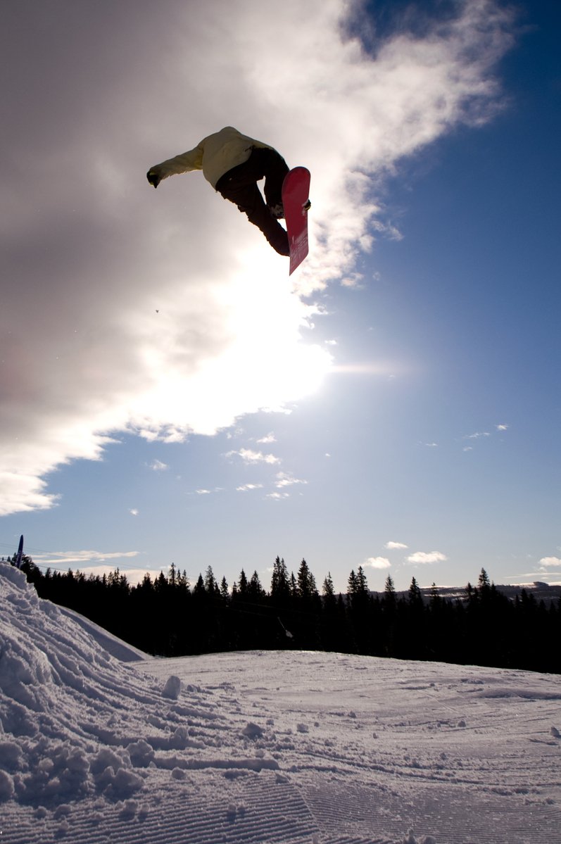 a snowboarder doing a trick in the air on a snowy hill
