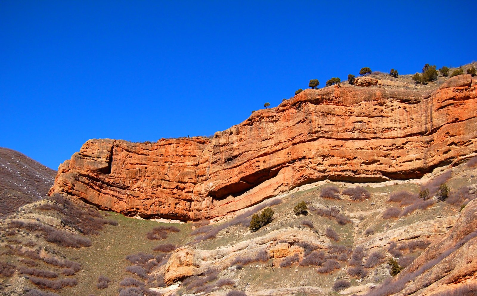 some brown rocks and green grass hills and clear blue skies