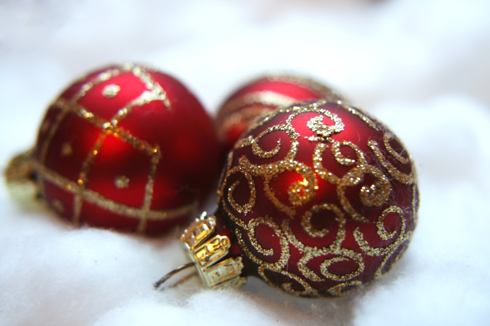two red ornaments in gold foil on a white surface
