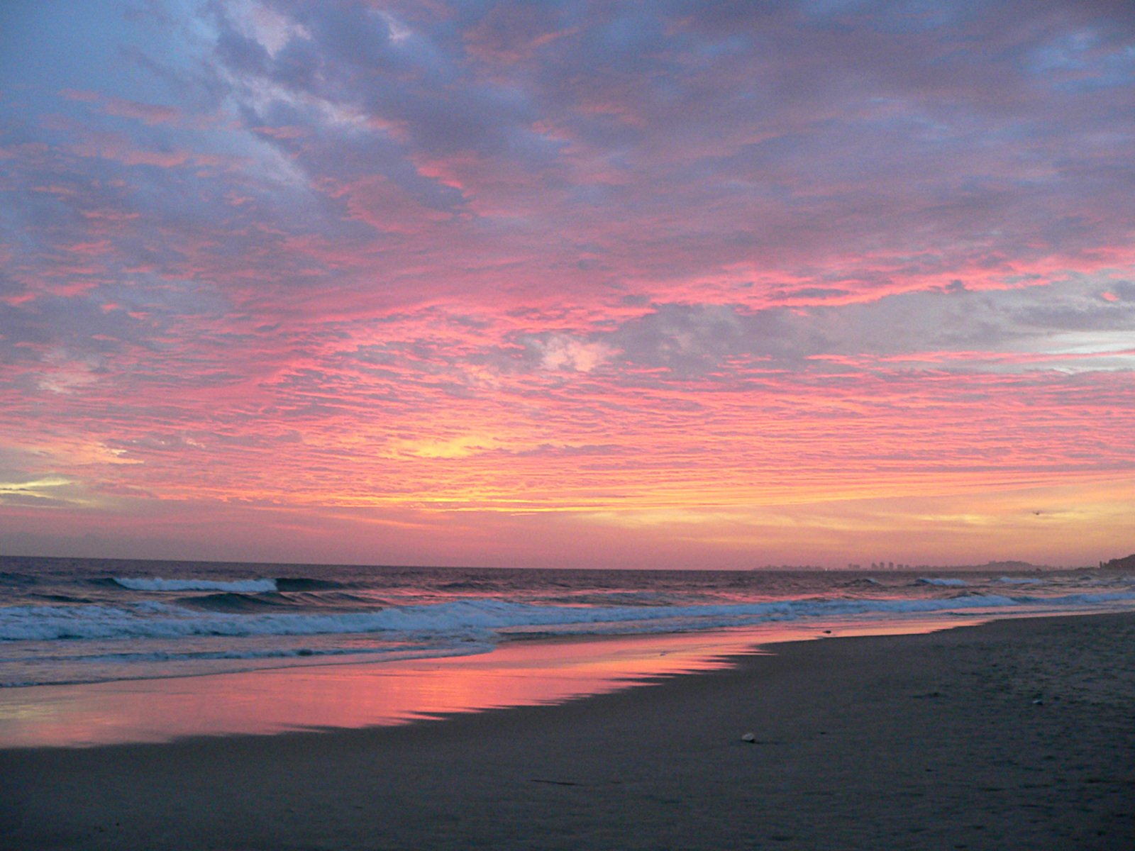 a sunset at the beach with waves coming in