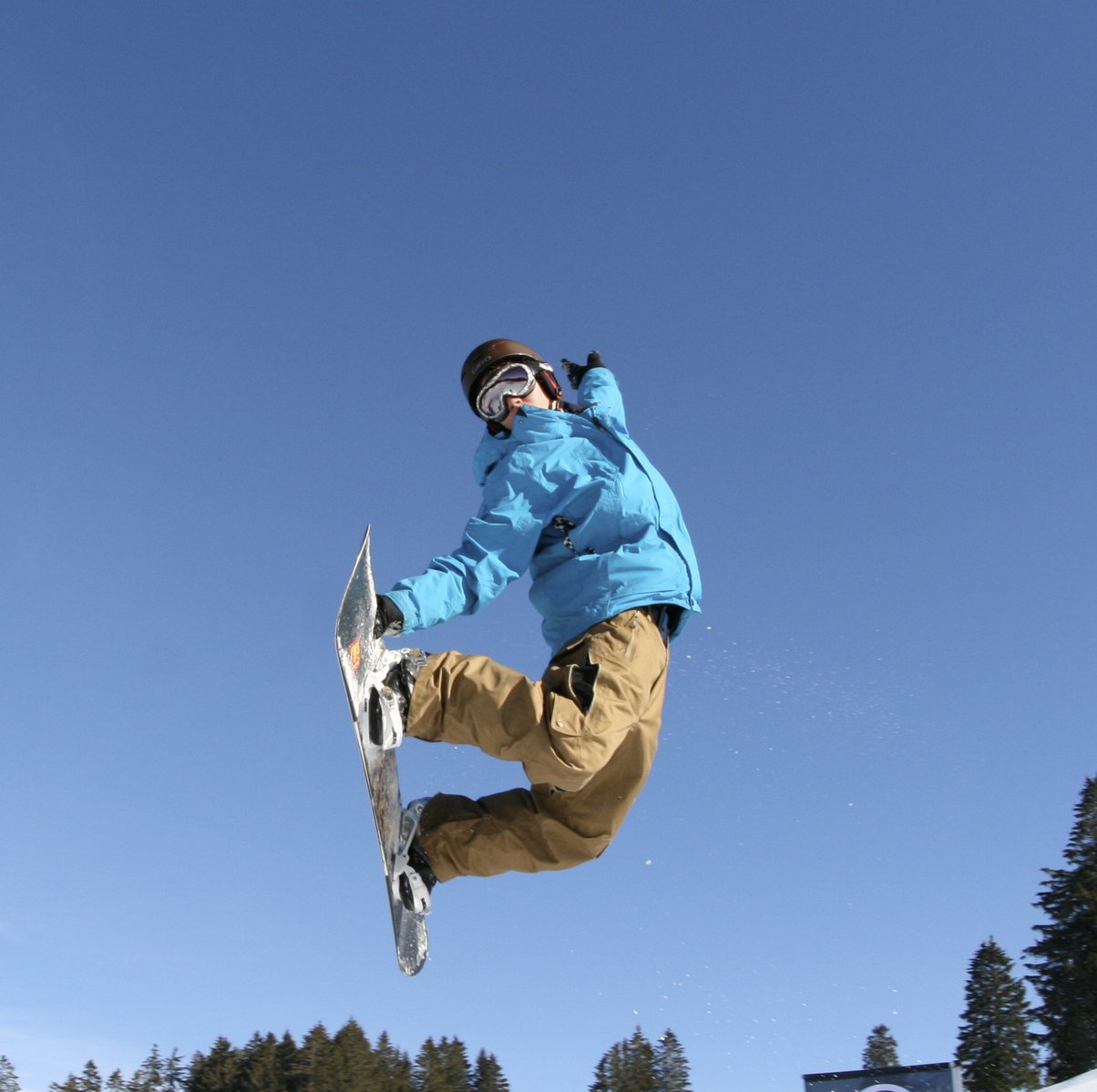 a snow boarder doing a flip on a sunny day