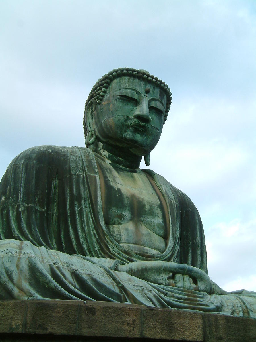 the large buddha is sitting under a cloudy sky