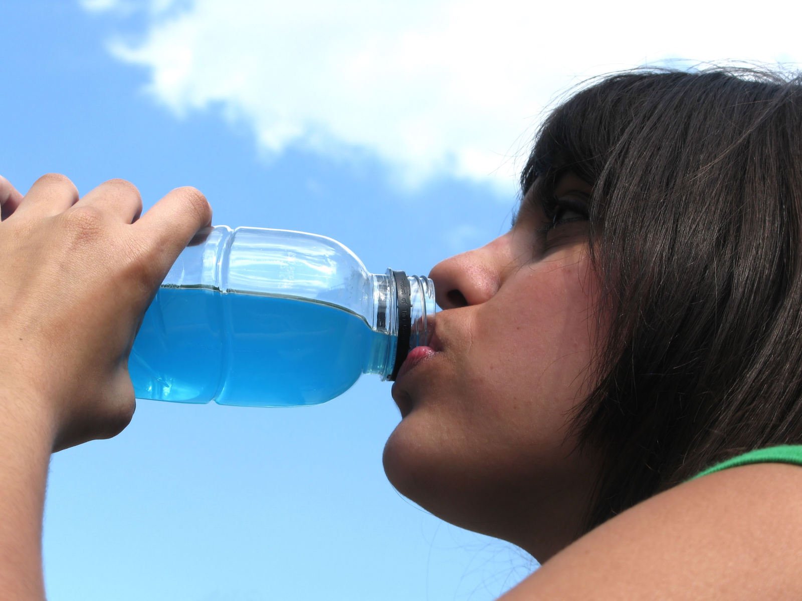 a woman drinking water from a bottle while outdoors