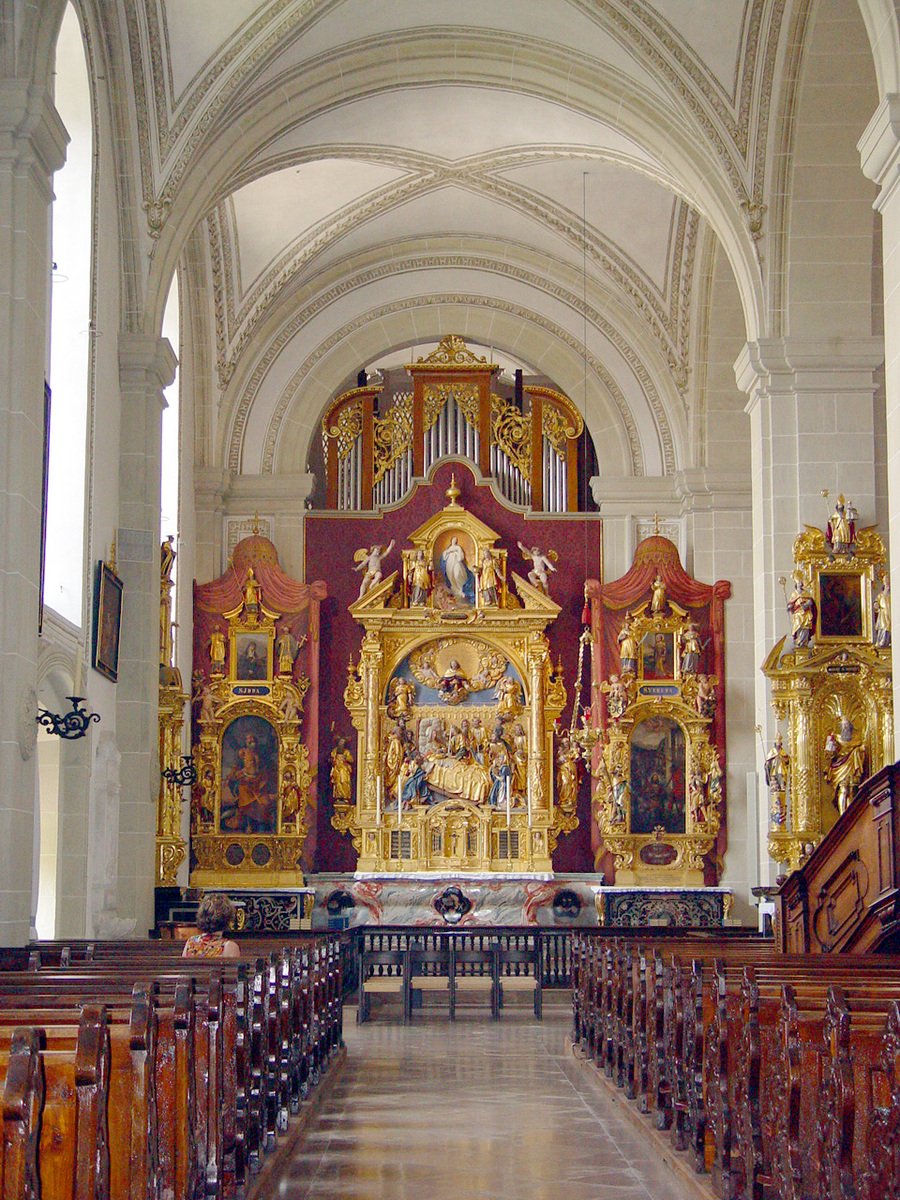 a church has an elaborately decorated alter and wooden benches