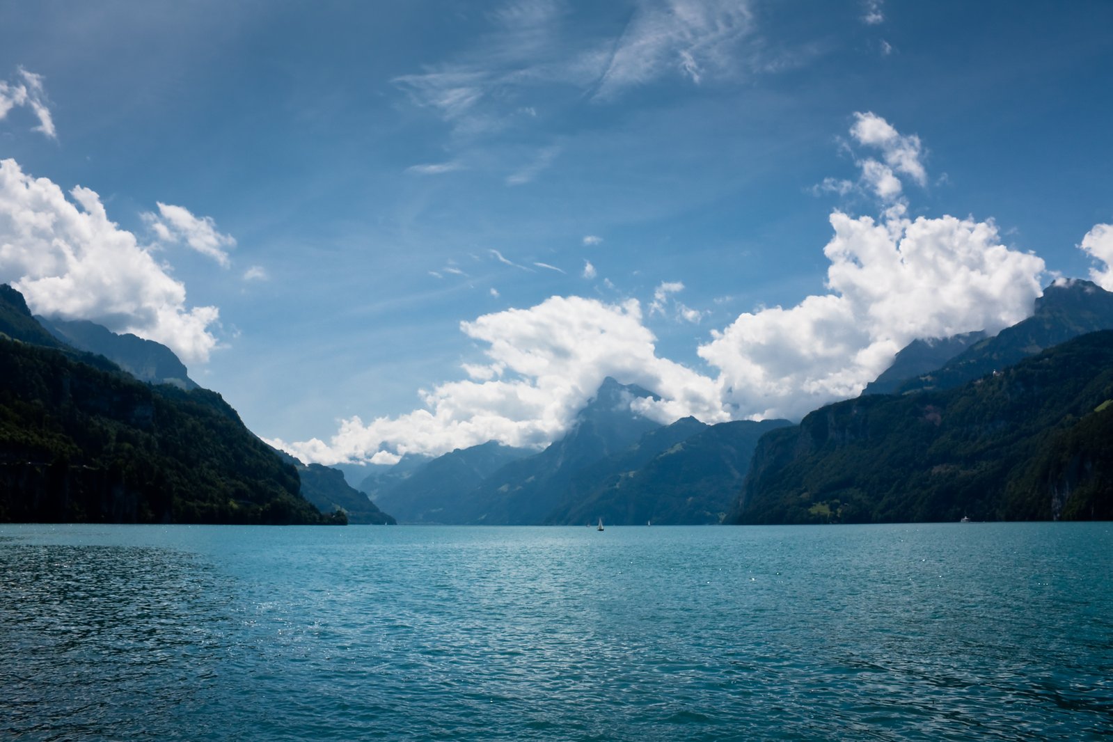 a body of water surrounded by mountains and clouds