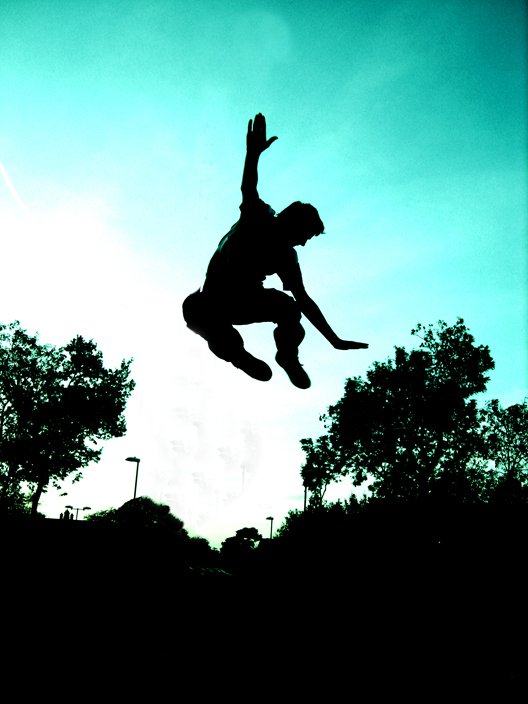 the silhouette of a person jumping in the air on a skateboard