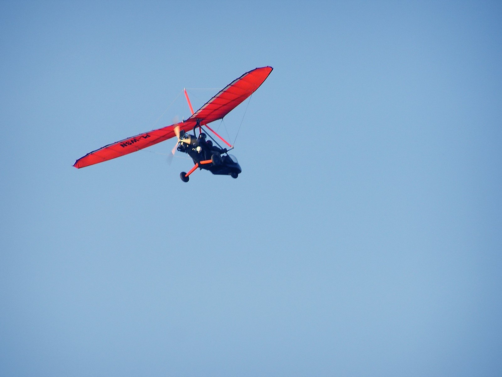 a man flying a red small plane through a blue sky