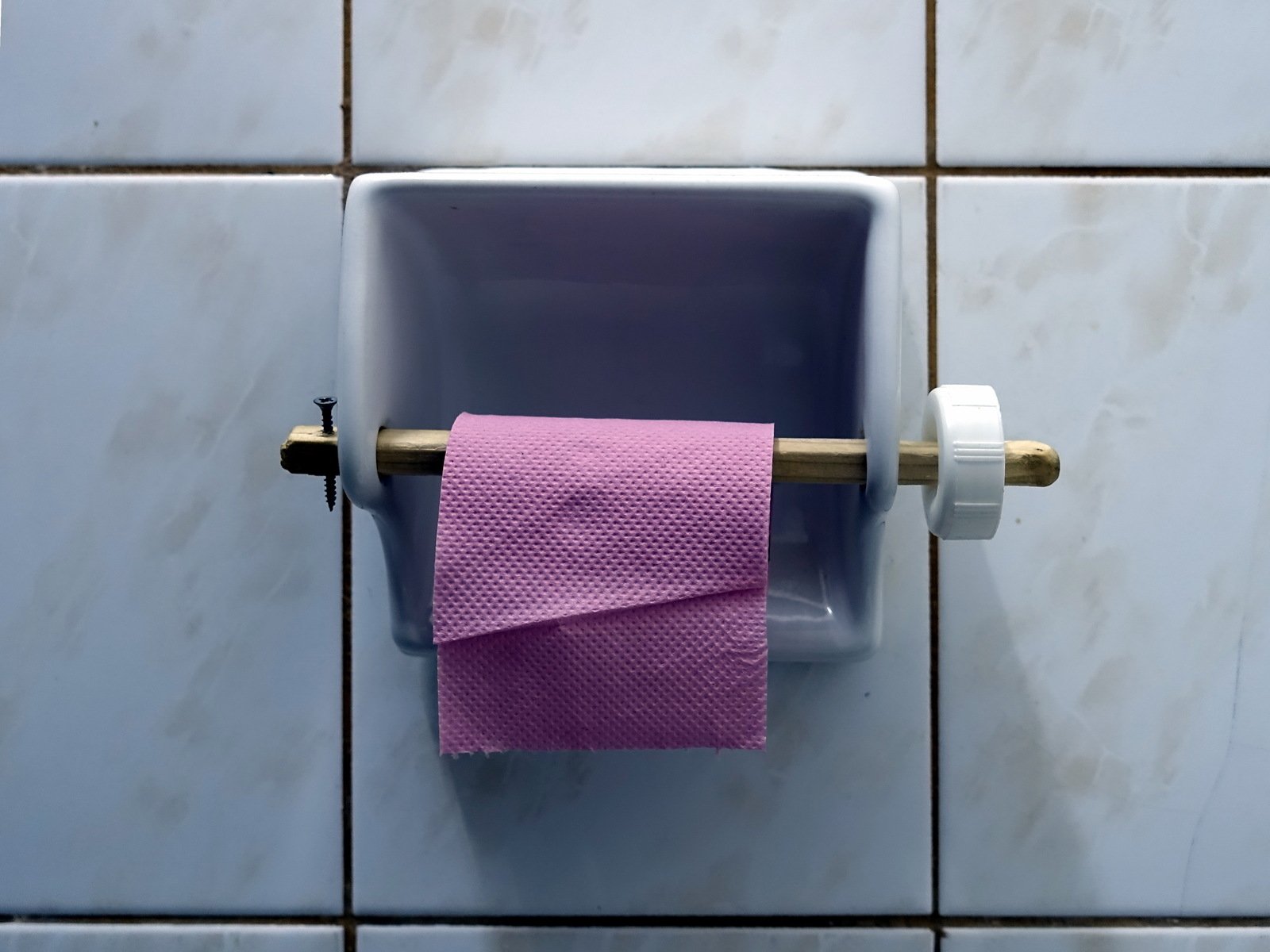 there is a roll of pink tissue sitting in the middle of a toilet