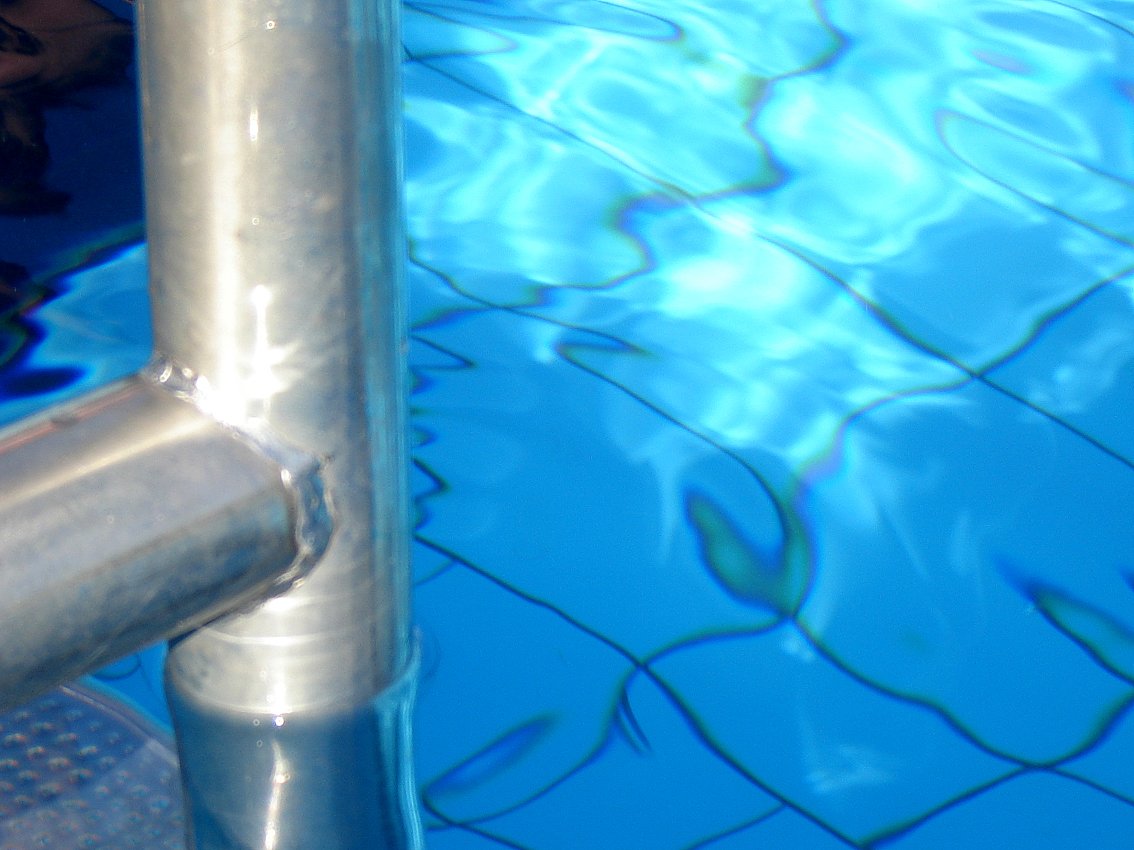 the swimming pool has clear blue water, but is reflecting the blue tiles