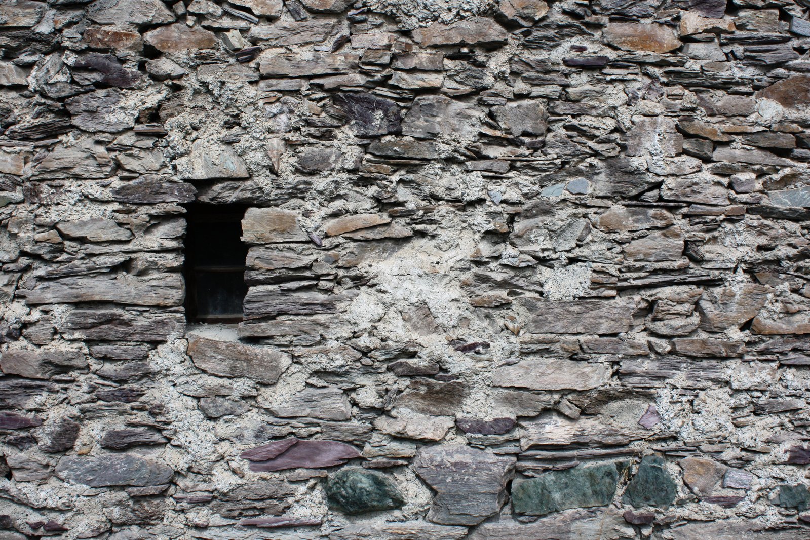 an old stone wall with a window in the center