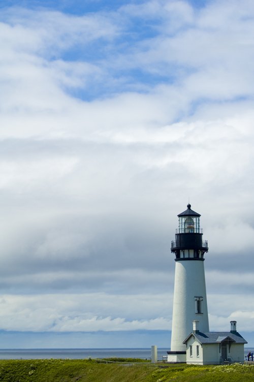 lighthouse on the beach with blue cloudy sky