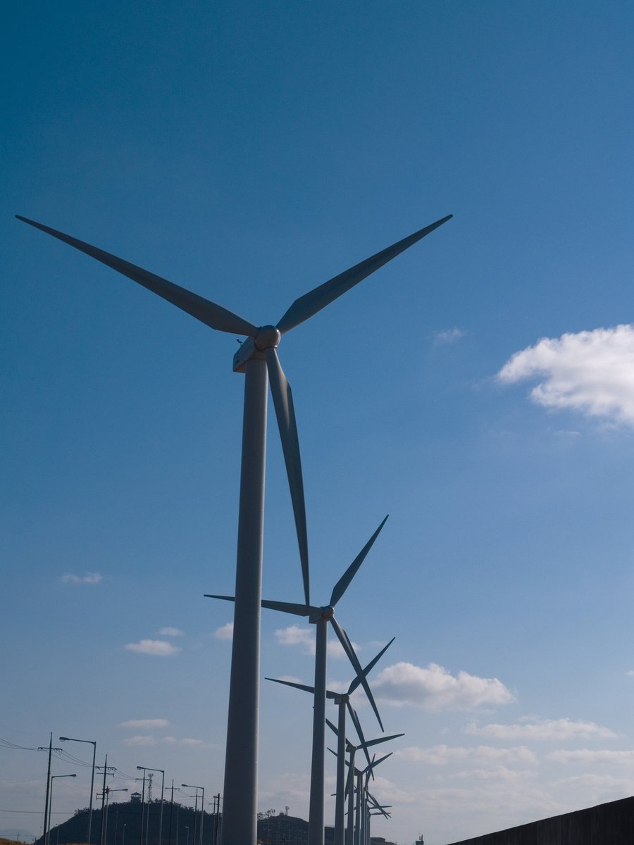 windmills stand next to each other in a grassy area