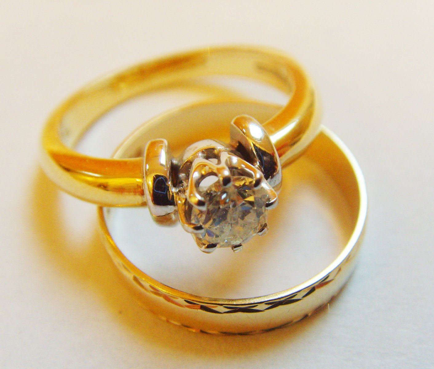 two gold rings are pictured with a diamond in the middle
