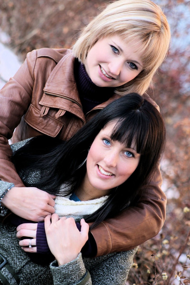 two beautiful young women hug and smile while looking in the camera