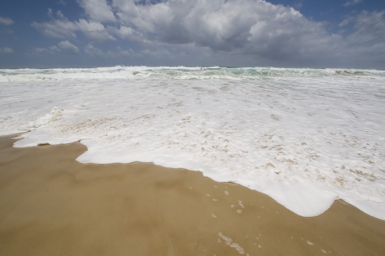 the shoreline has small waves crashing into it