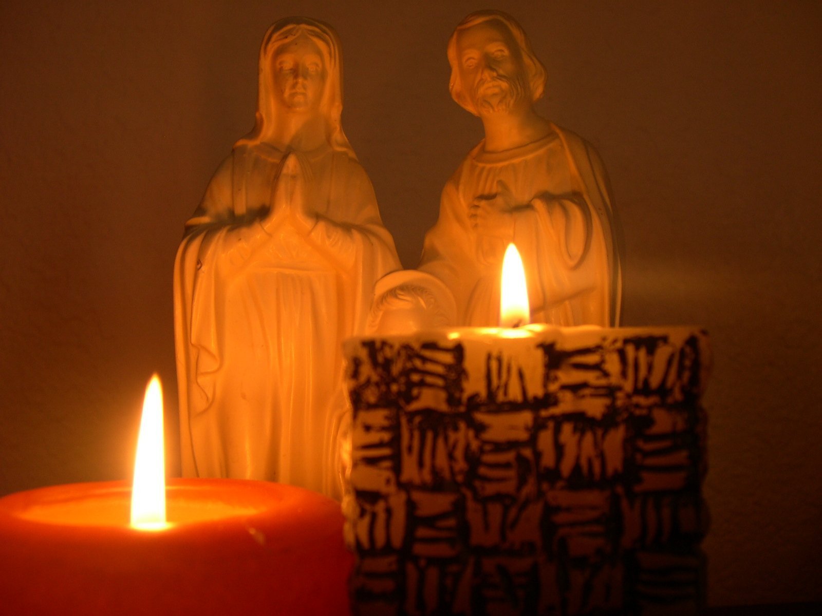 a lit candle sits between two small statues