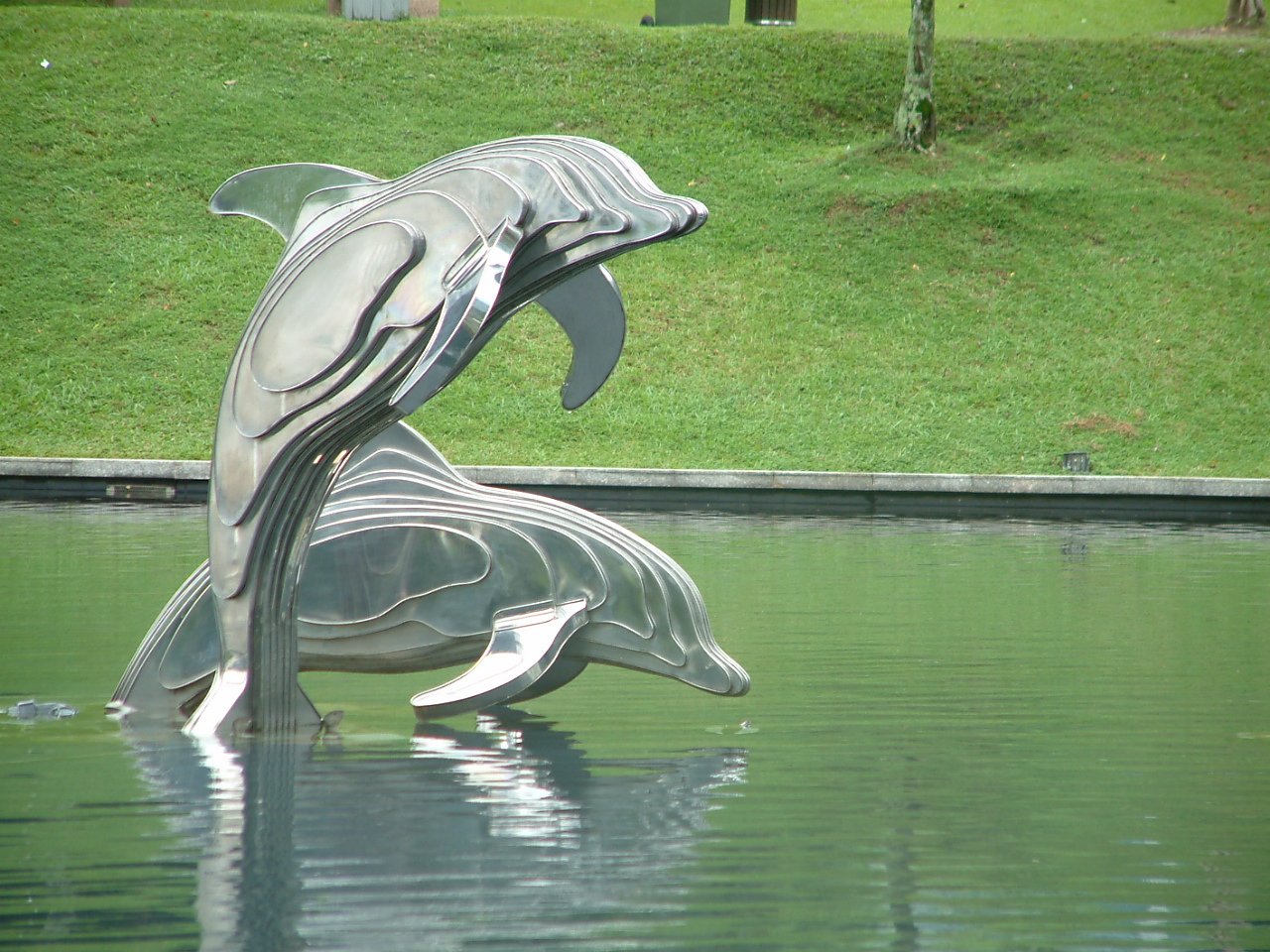 a metal dolphins sculpture is in the water