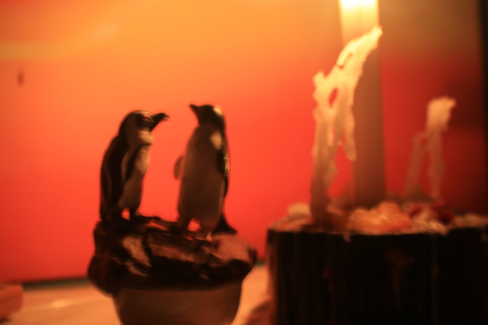 two penguins standing on top of an iced donut