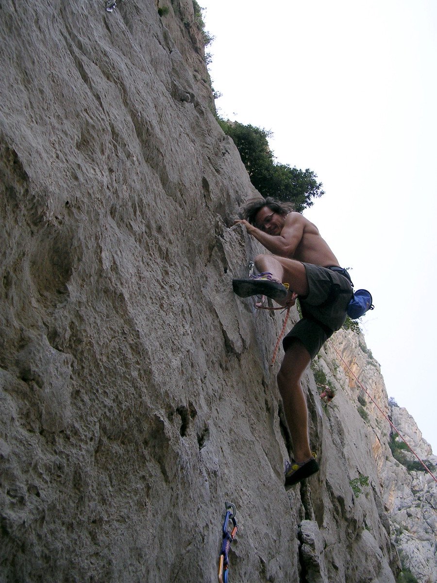 a man is climbing up a cliff wearing hiking shoes