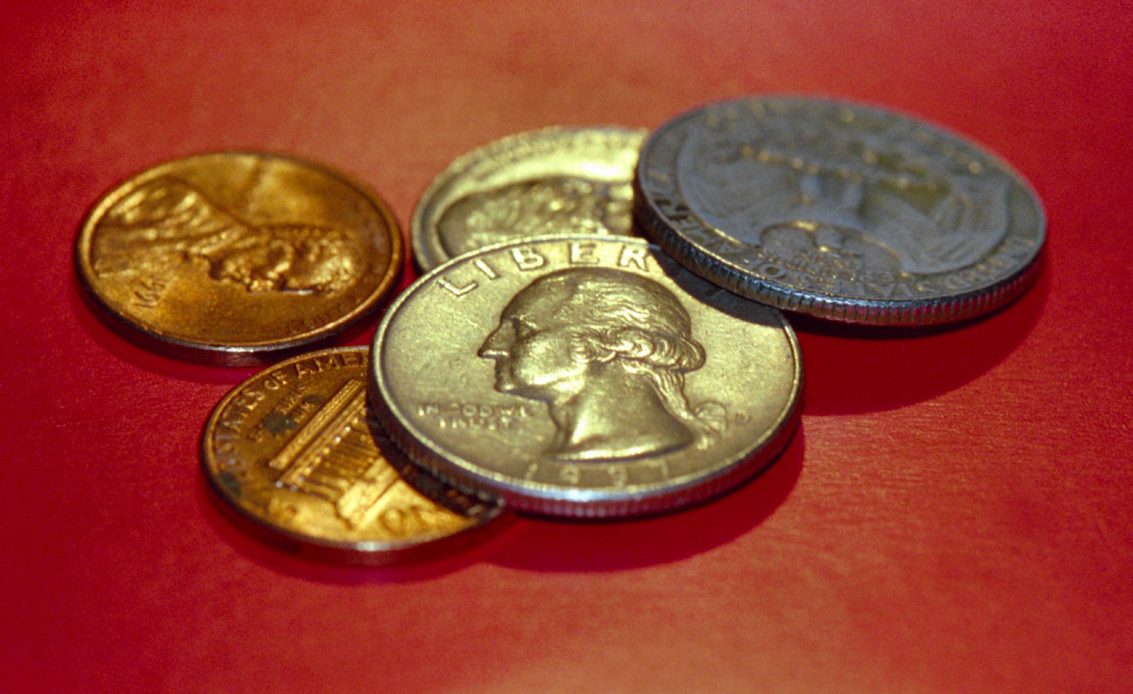 a pile of different colored coins on red surface