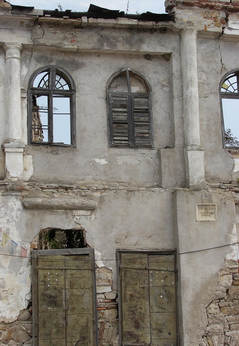 an old dilapidated house with three doors and three windows