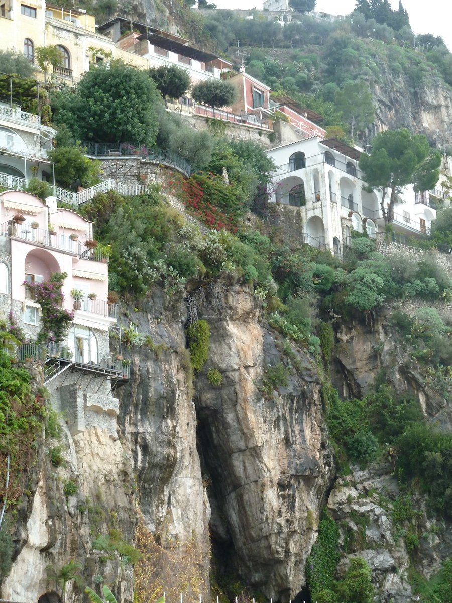 an uphill cliff houses and a boat parked by the water