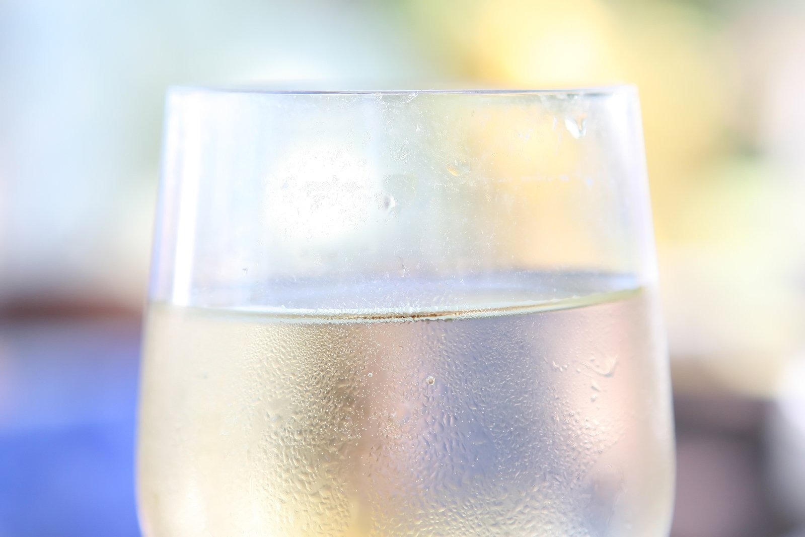 a glass filled with white wine sitting on top of a table