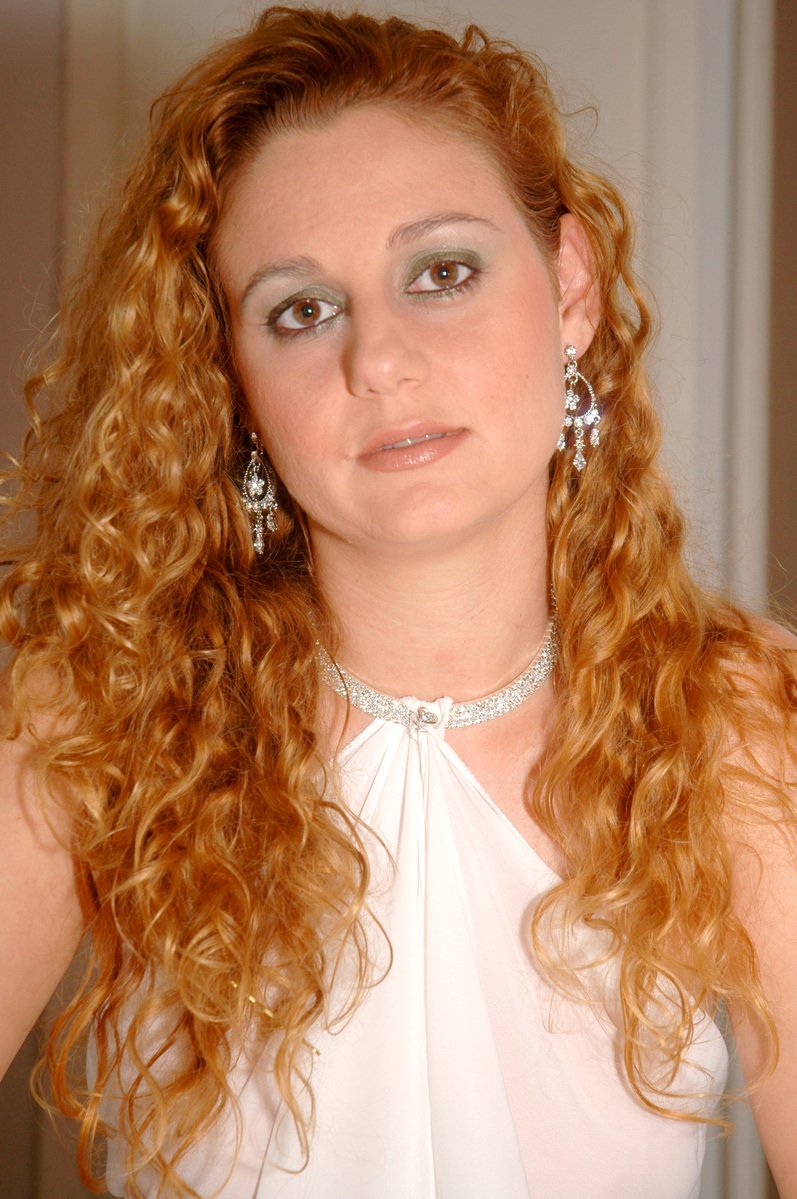 a woman with big, curly hair wearing statement earrings