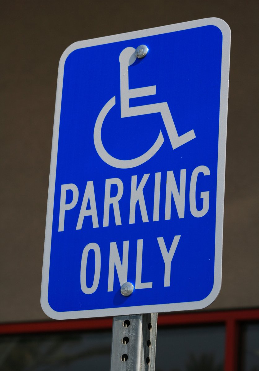 a handicapped parking sign attached to a pole