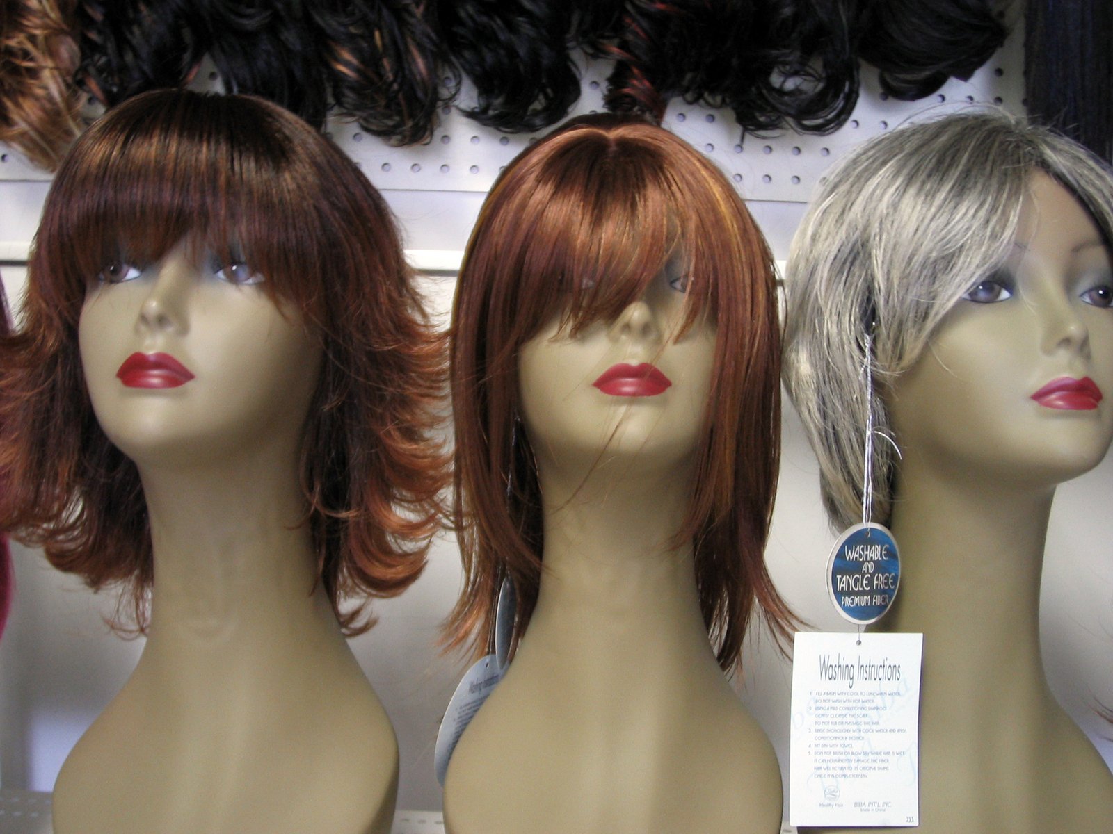 several wigs are lined up on display on a wall