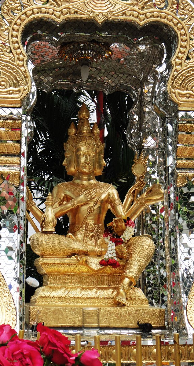 gold statue sitting in front of a floral arrangement