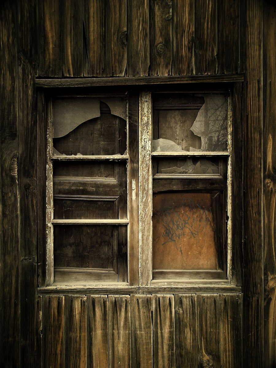 a broken glass window in a wooden building