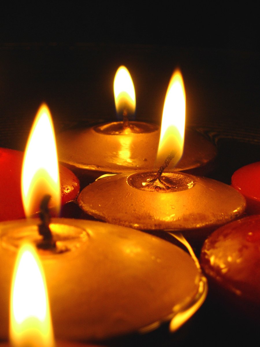 three lit candles in front of red candles