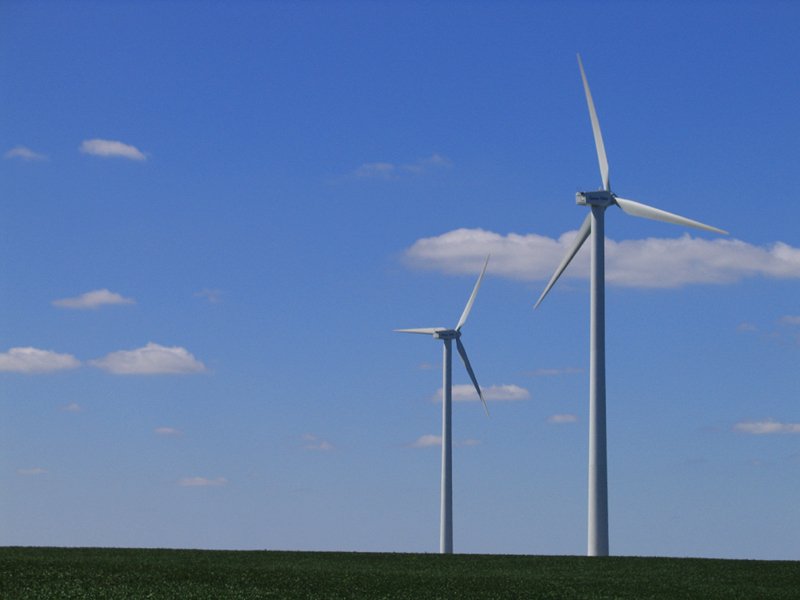 many windmills on a grassy field with a blue sky in the background