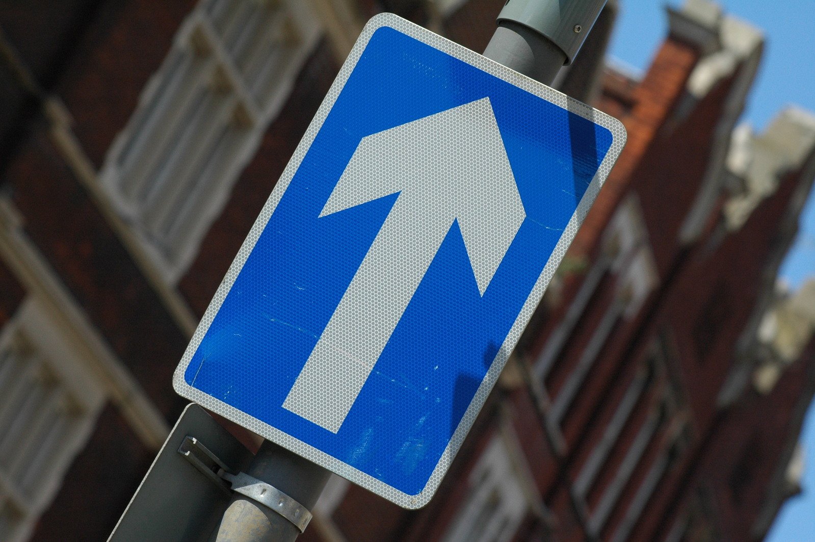 a blue street sign pointing up the side of a building